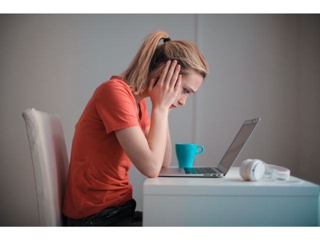 パソコンの前で悩む女性